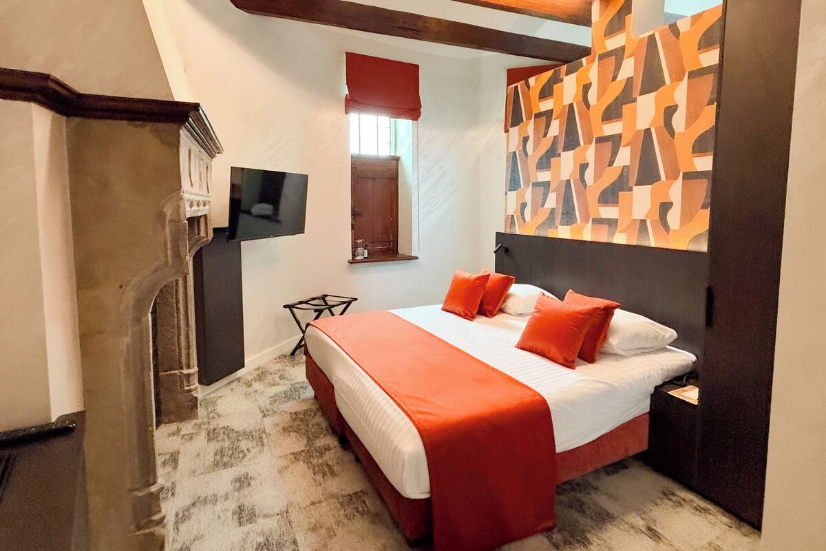 Habitación de hotel con cama, televisión, cabecera de madera y pared con diseño.