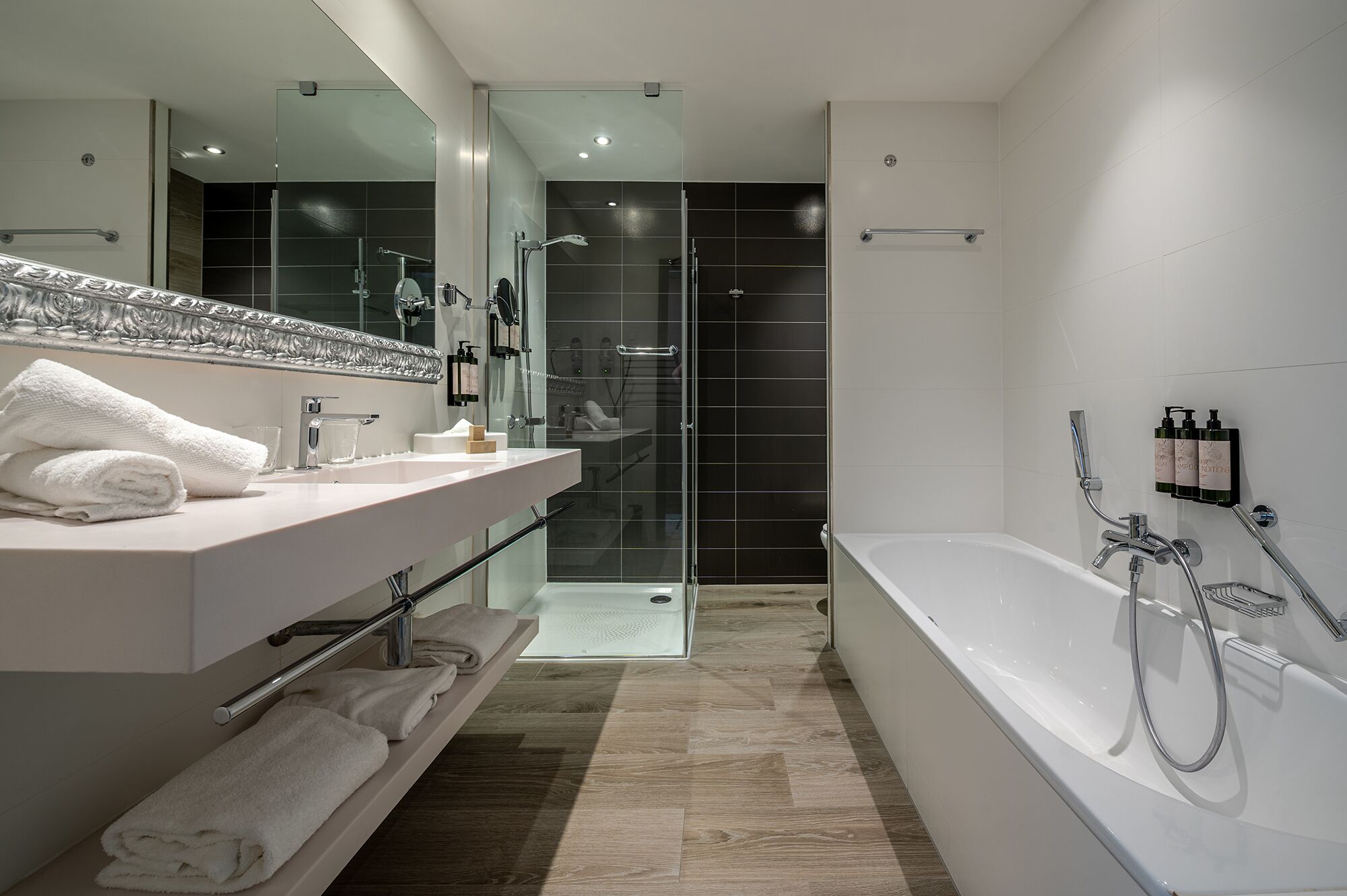 A modern bathroom with a large mirror, white vanity, and a walk-in shower.