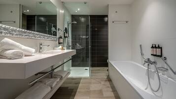 Une salle de bain moderne avec un grand miroir, un meuble-lavabo blanc et une douche à l’italienne.
