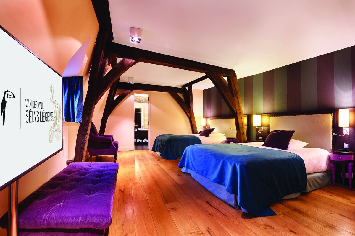 Una habitación de hotel con dos camas, un banco y un ventanal grande.