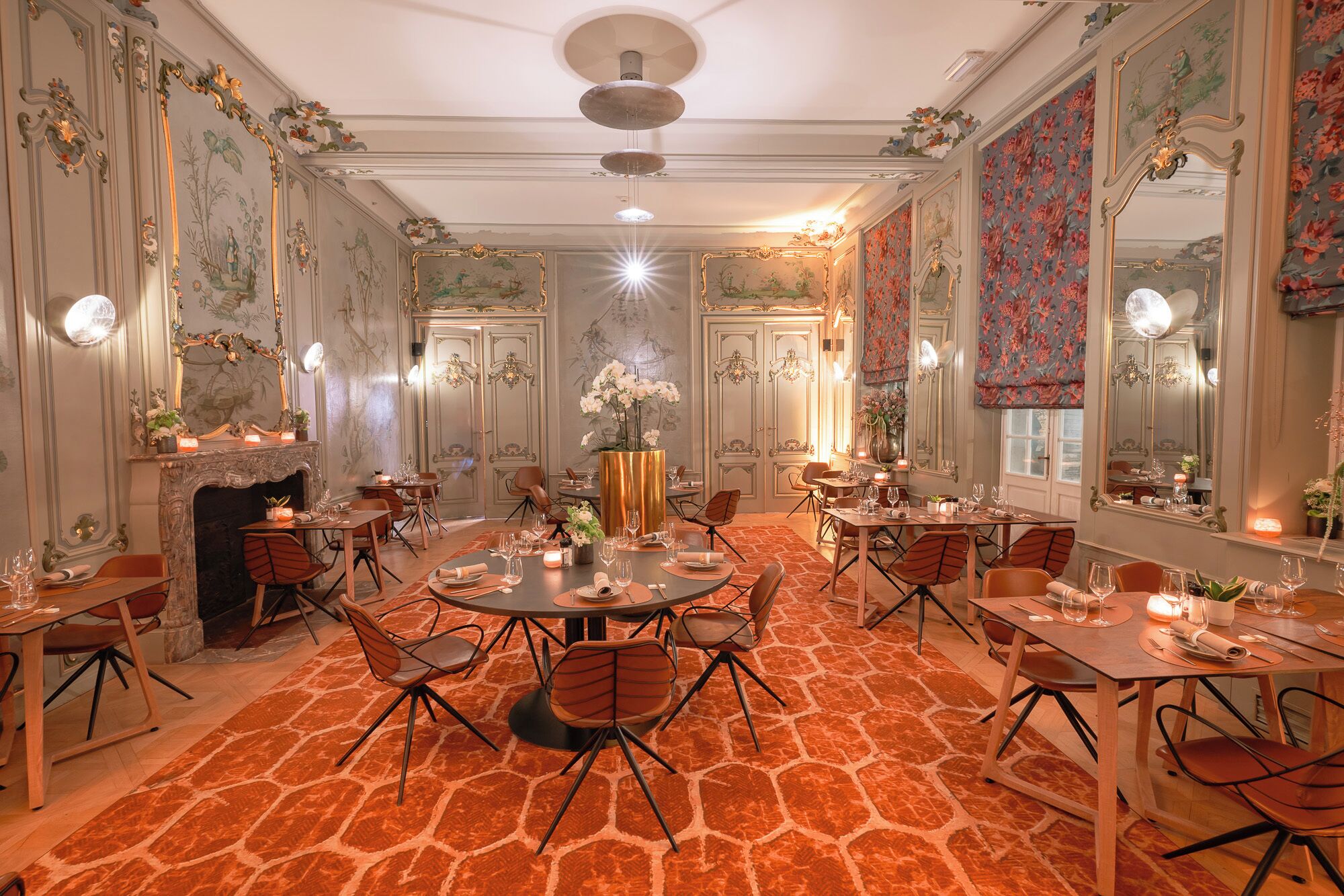 Una sala de dinar formal amb decoració elaborada, diverses taules i cadirees.
