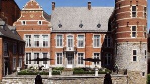 Een binnenplaats met terras en een historisch gebouw met een bakstenen gevel en een ronde toren.