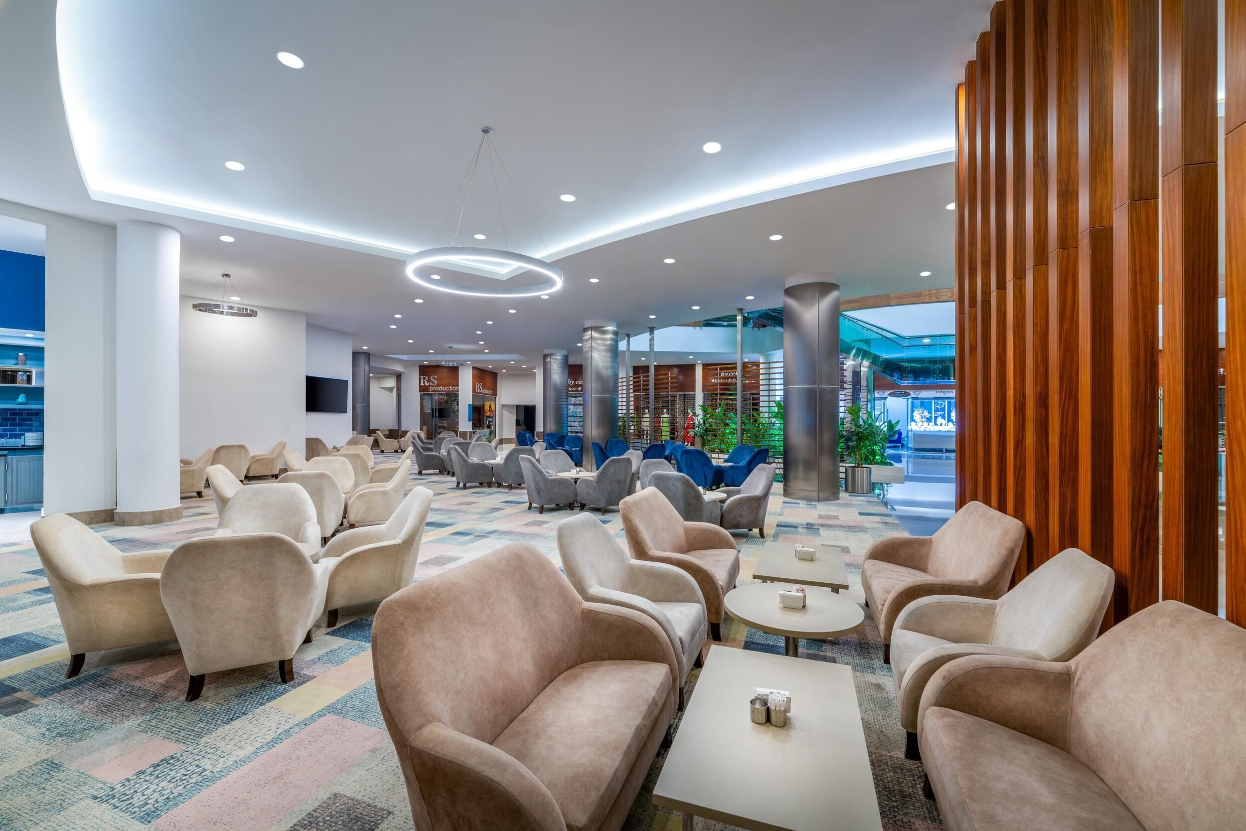 A spacious lobby with multiple seating areas, including sofas and armchairs, arranged around tables.