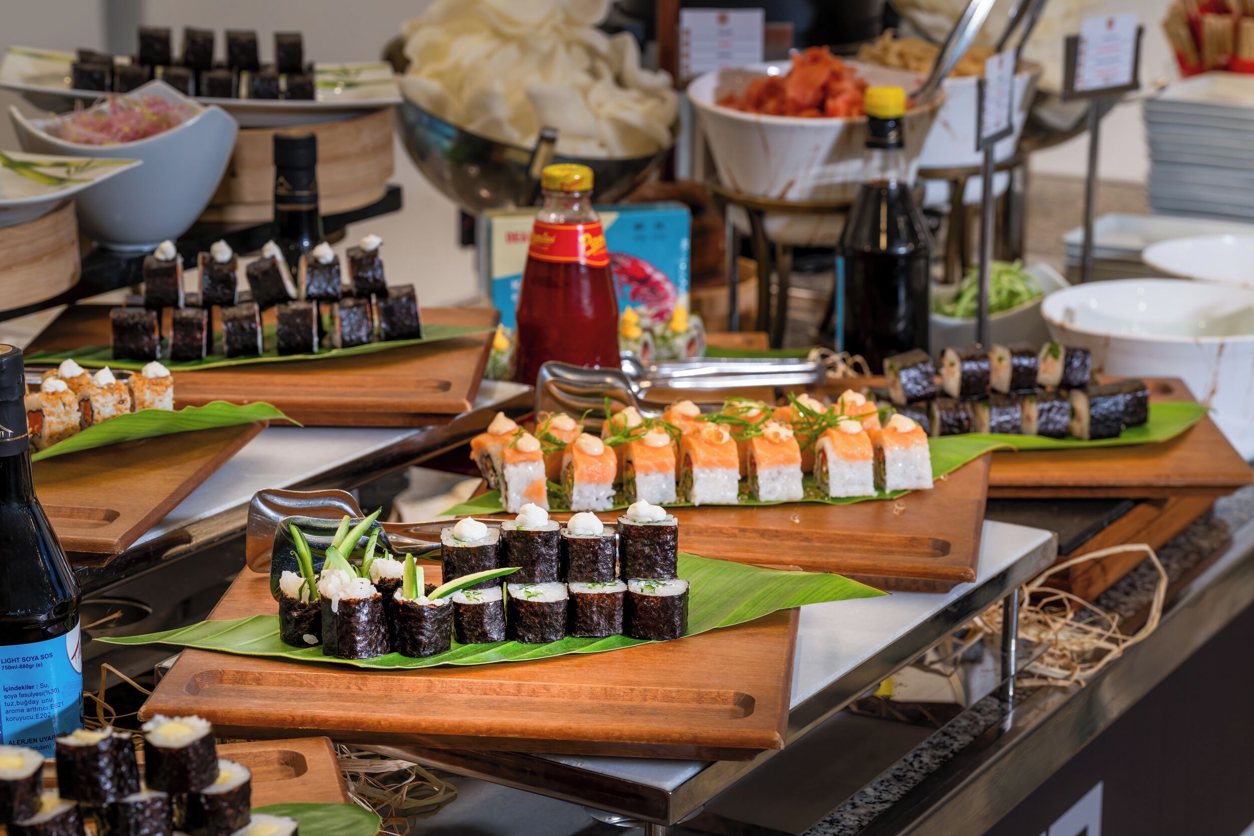 A buffet with various sushi dishes and condiments.