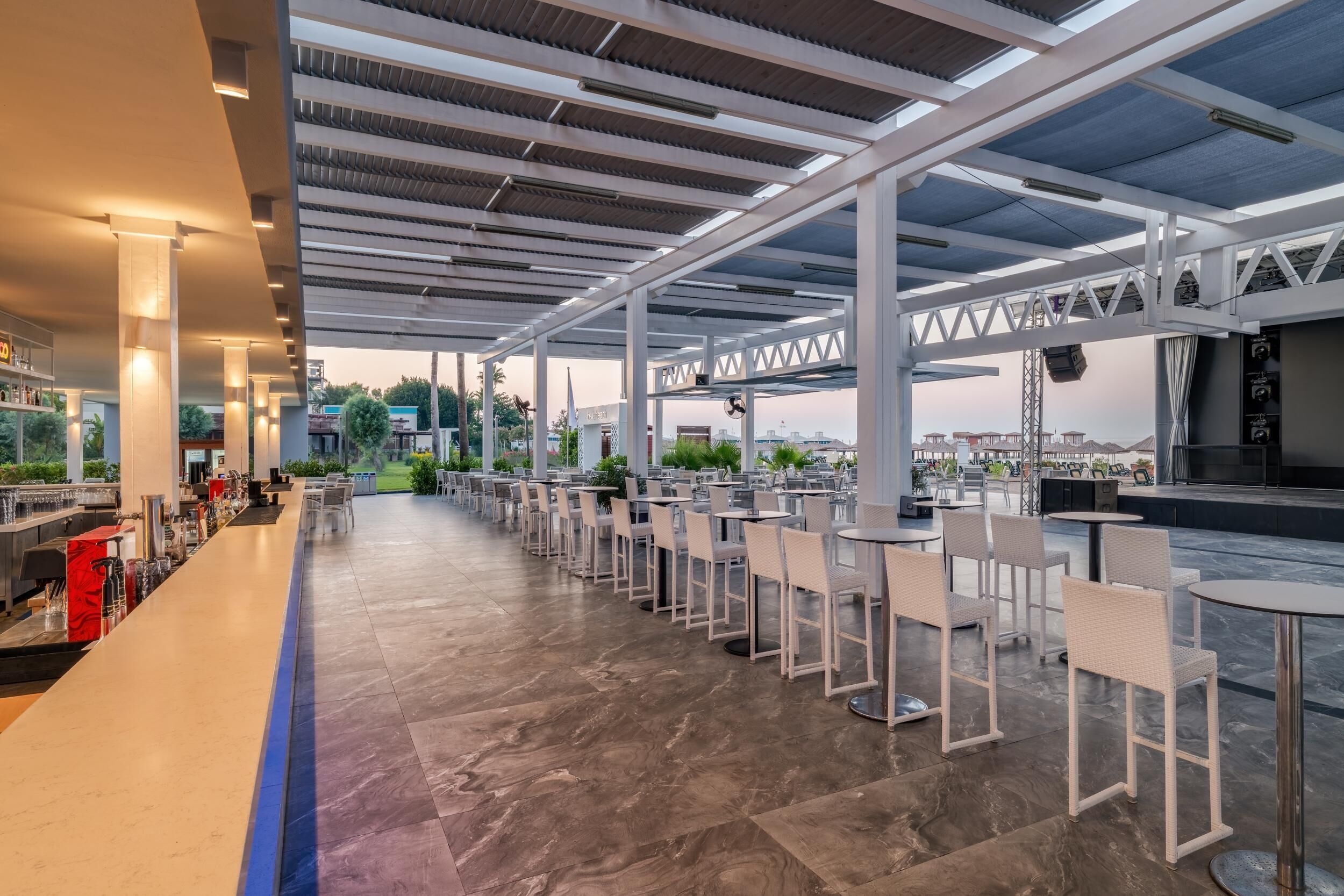 A spacious outdoor seating area with tables and chairs, a bar counter, and a view of the cityscape.
