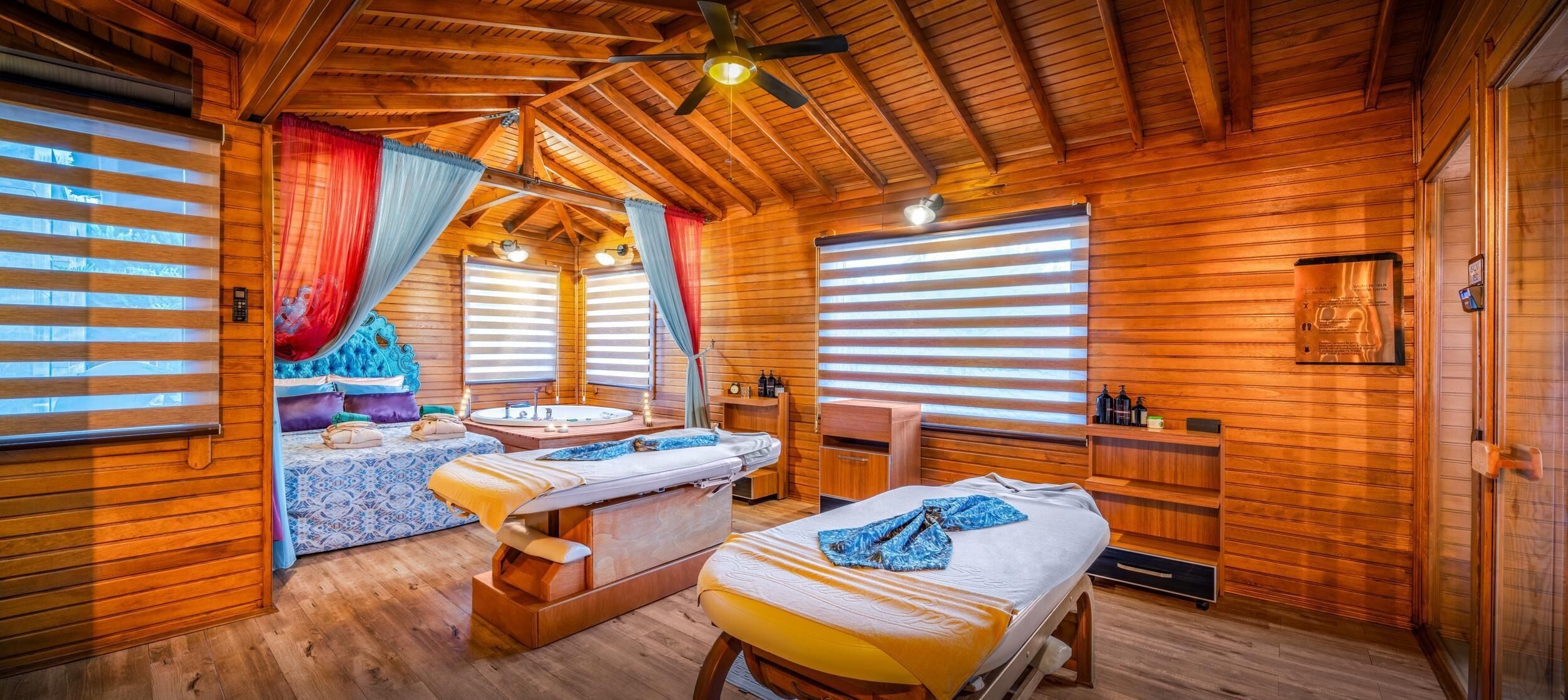 Een houten hut met twee bedden, een massagetafel en een sauna.