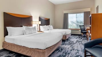 A hotel room with two beds, a desk, a chair, and a large window.