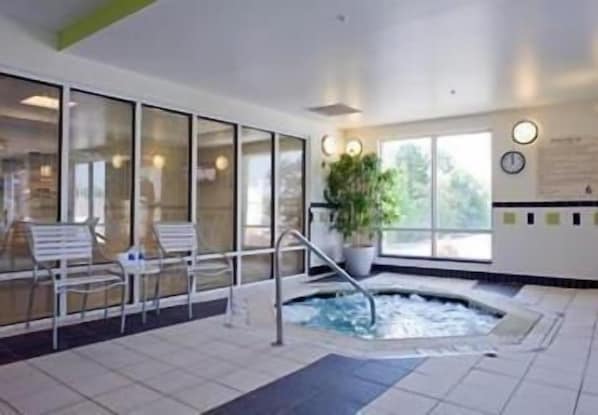 Un área de spa con hidromasaje, zona de estar y ventanas amplias.