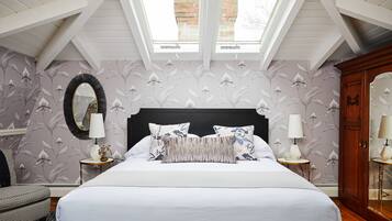 A bedroom with a large bed, two bedside tables with lamps, a mirror, and a wardrobe.