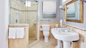 Une salle de bain avec une douche à parois de verre, des toilettes et un lavabo.