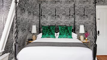 Una camera da letto con una testiera a motivi zebrati, un letto con biancheria da letto bianca, cuscini verdi e un comodino con una lampada e un vaso di fiori.