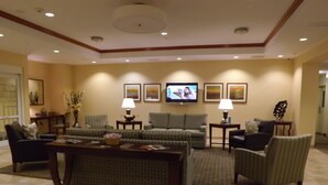 A hotel living room with a sofa set, a coffee table, a TV, and framed artwork on the wall. - Candlewood Suites Fredericksburg by IHG (Fredericksburg)