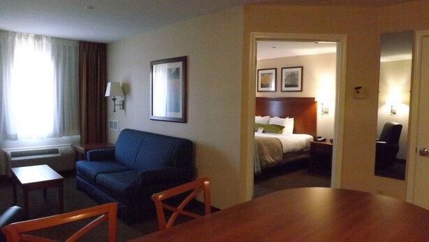 A hotel room with a bed, a sofa, a dining table, and a small table with a chair.