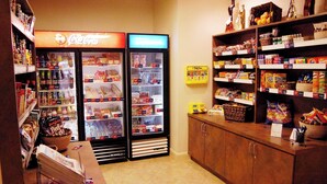 A convenience store with refrigerated sections, shelves stocked with snacks, and a Coca-Cola cooler. - Candlewood Suites Fredericksburg by IHG (Fredericksburg)