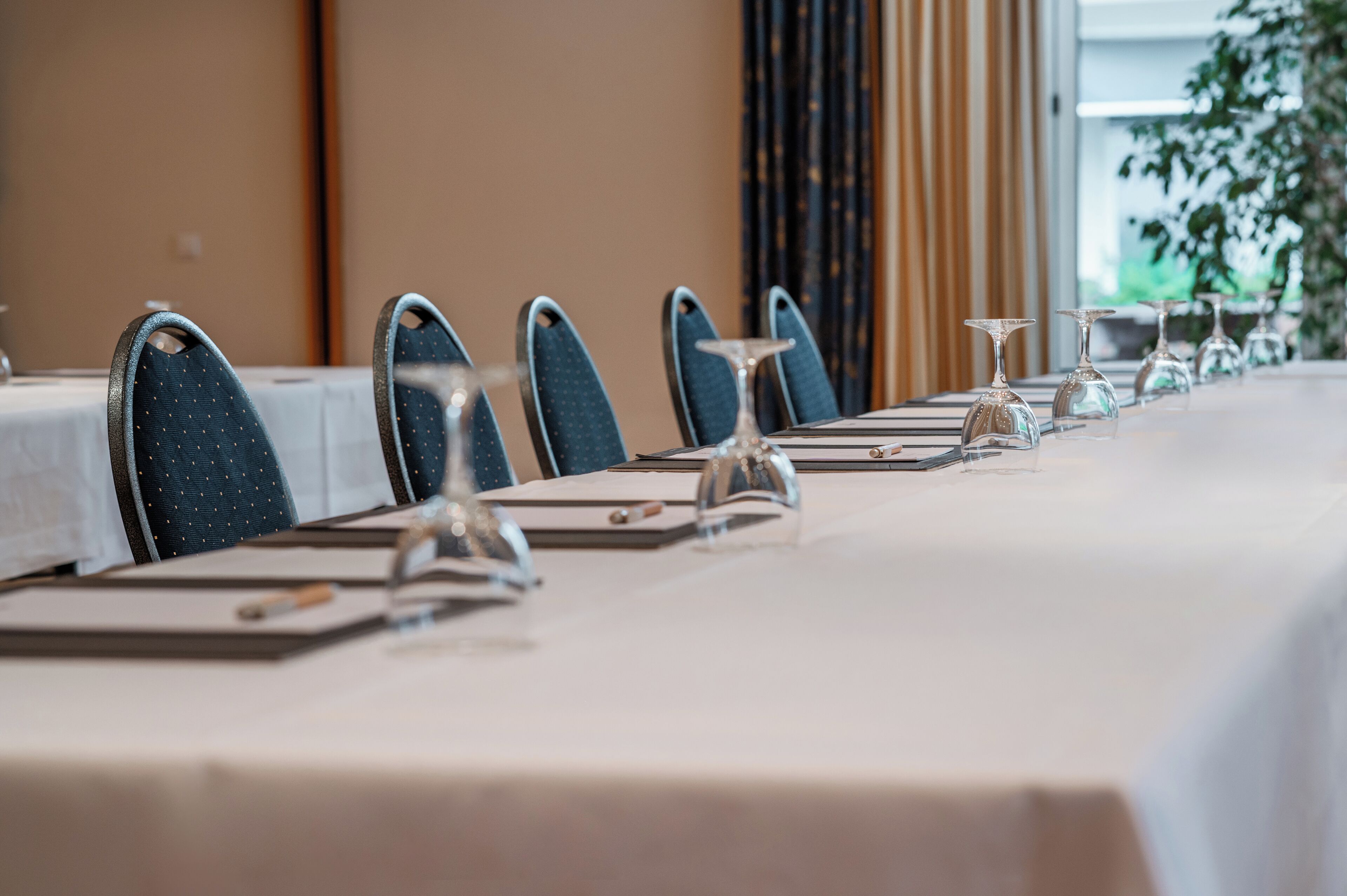 A conference table set with chairs, documents, and wine glasses.
