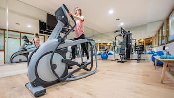 A modern gym with a stationary bike, exercise balls, and various fitness equipment.