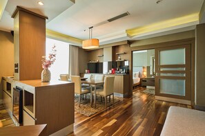 A modern hotel room with a wooden floor, a dining area, a kitchen, and a separate bedroom with a large window. - Avantgarde Urban Levent (Istanbul)