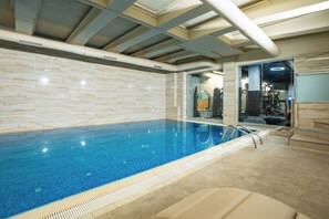 An indoor swimming pool with a clear blue water surface, surrounded by beige walls and a tiled floor. - Avantgarde Urban Levent (Istanbul)
