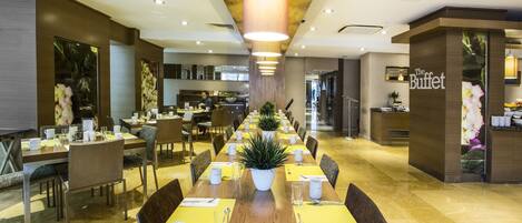 A spacious dining area with long tables, chairs, and a central plant.