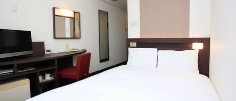 Une chambre d’hôtel avec un lit, un bureau avec une télévision, une chaise et un miroir.