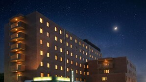 A multi-story hotel with illuminated windows and balconies, a sign indicating 'Urban Hotel Kyoto,' and a clear night sky with stars and a crescent moon. - Urban Hotel Kyoto (Kyoto)