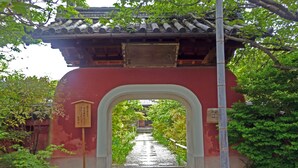 A traditional Japanese gate with a tiled roof, leading to a pathway surrounded by greenery. - Urban Hotel Kyoto (Kyoto)