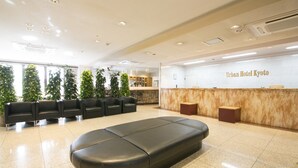 A hotel reception area with a reception desk, seating area, and a large black bench. - Urban Hotel Kyoto (Kyoto)