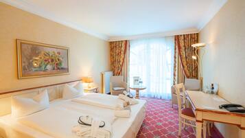 A hotel room with a large bed, a desk, a chair, a lamp, and a painting on the wall.