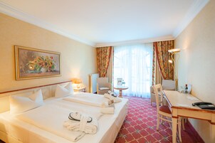 Quarto de hotel com uma cama grande, uma mesa de escritório, uma cadeira, um abajur e um quadro na parede.