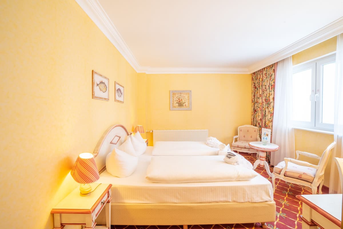 Une chambre d’hôtel avec deux lits, une petite table, une chaise et un radiateur.