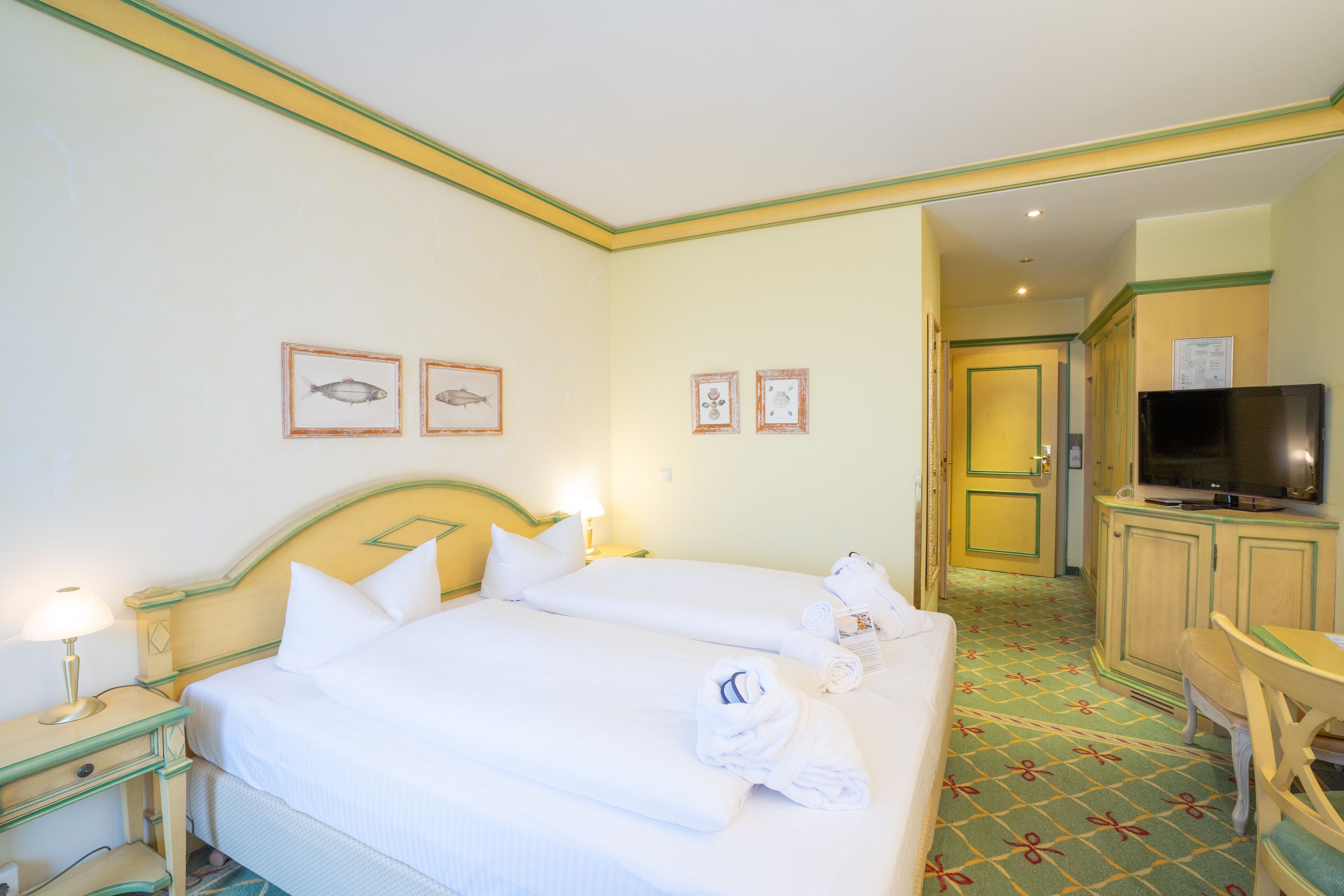 A hotel room with two beds, a television, a desk, and a chair.