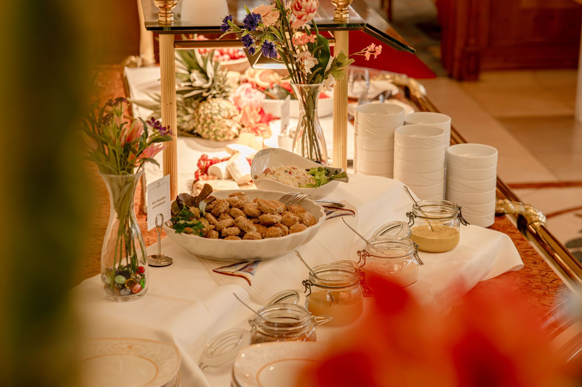 Une table de buffet proposant divers plats, notamment un panier de petits pains, une salade et un bocal de sauce.