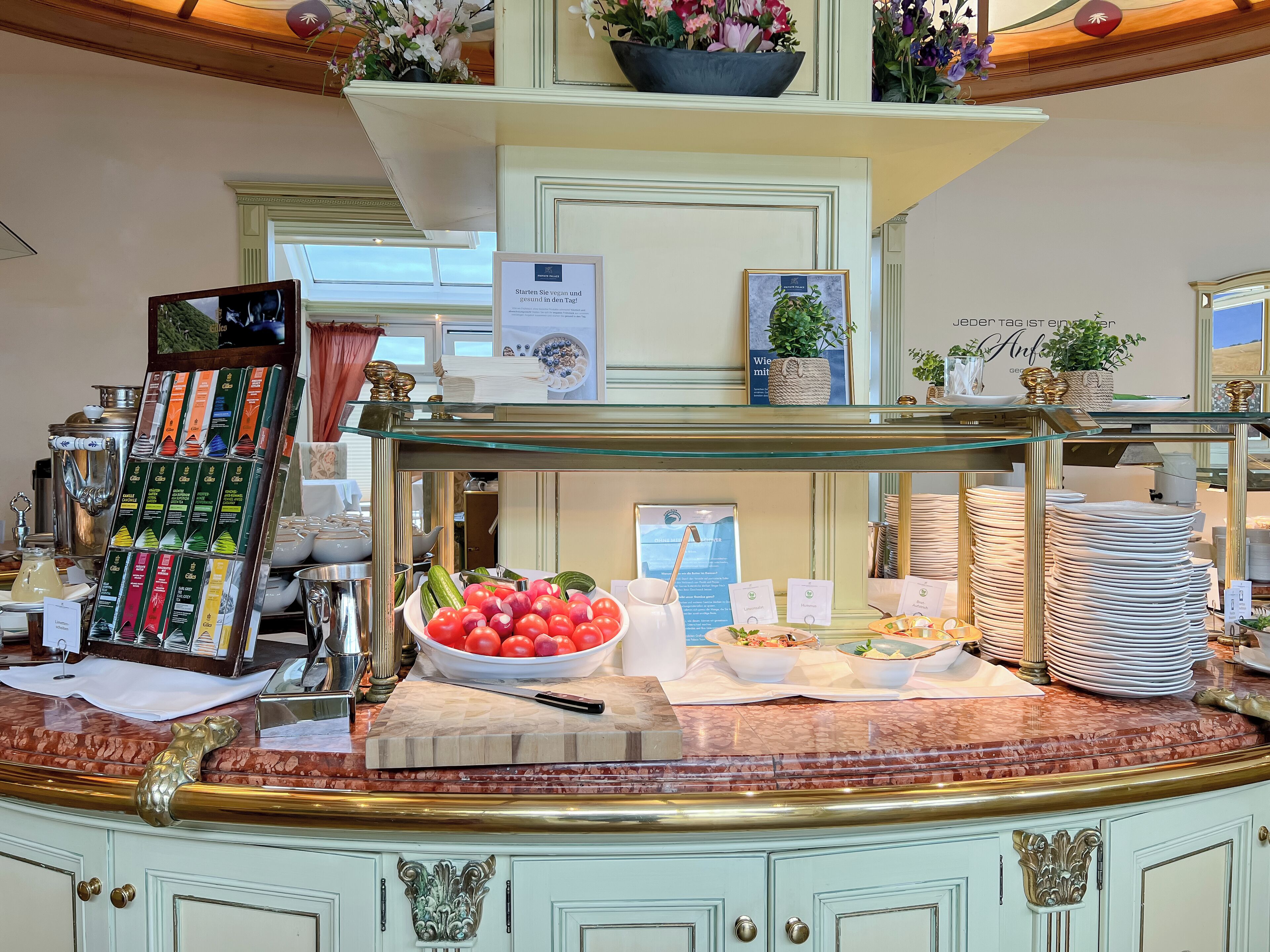 A buffet counter with various food items, including a bowl of tomatoes and cucumbers, and a display of packaged snacks.