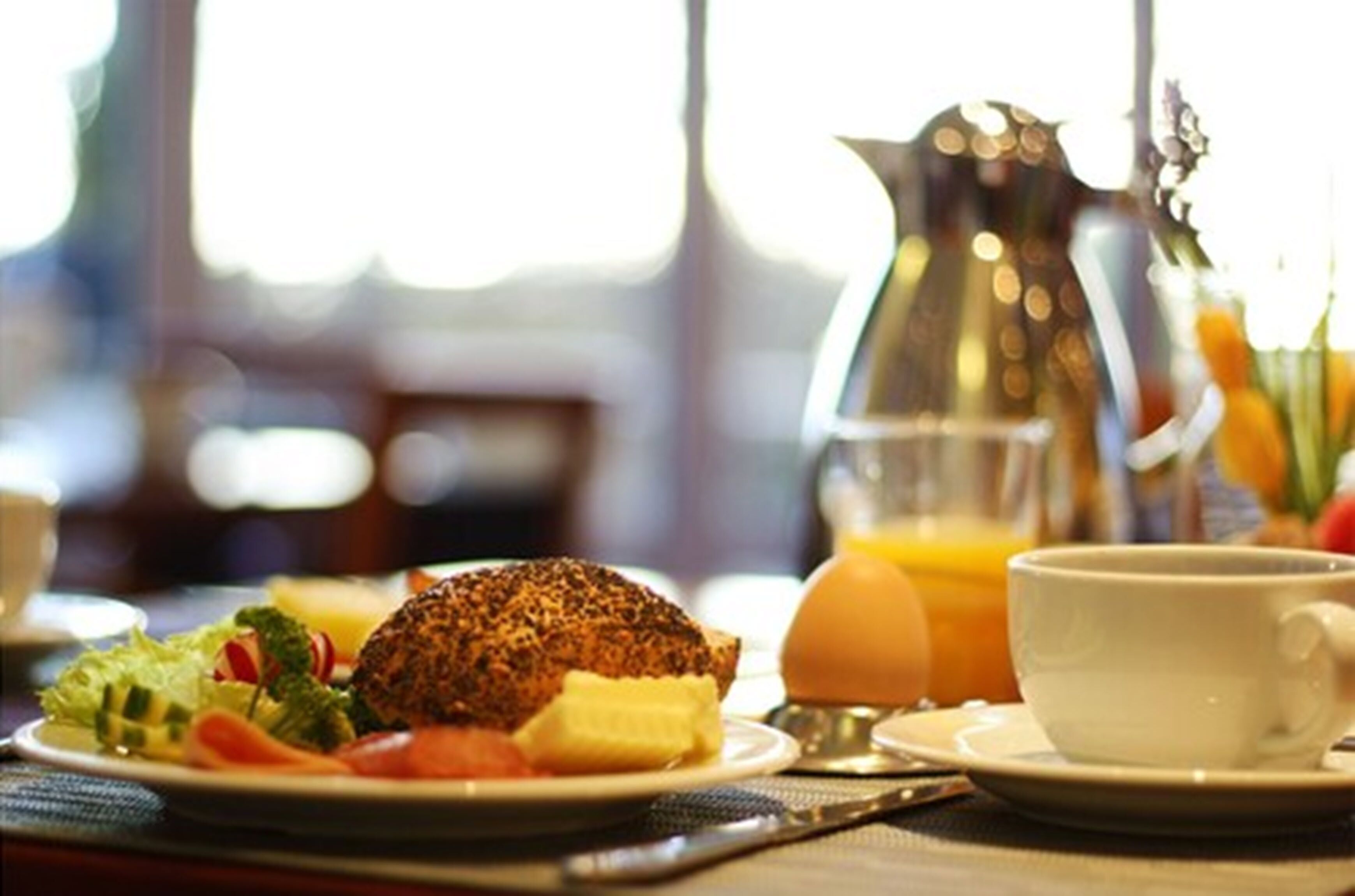 A breakfast setting with a plate of food, a cup of coffee, and a pitcher of orange juice.