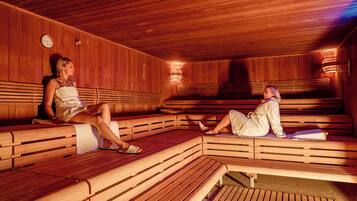 A wooden sauna with benches and a clock on the wall.