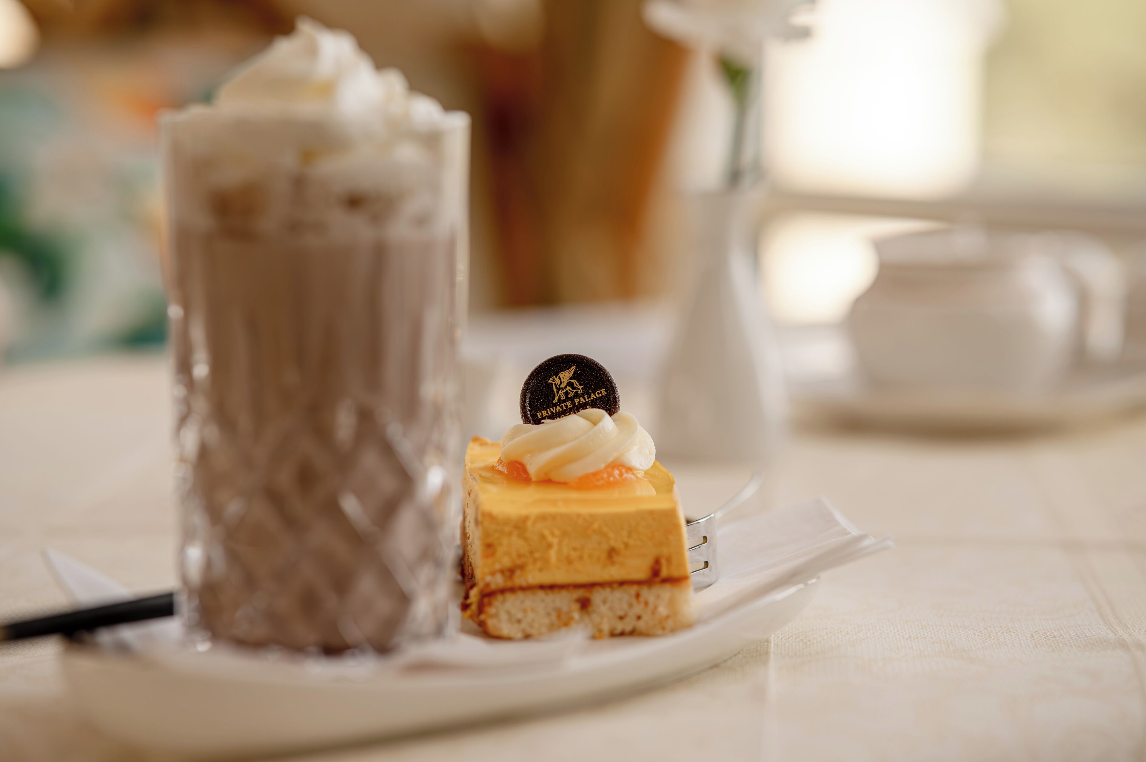 Sobremesa com camada de chocolate e cobertura de creme, servida num prato branco.