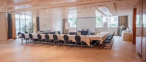 A conference room with a long table, chairs, a projector screen, and a whiteboard.