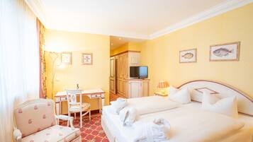A hotel room with a bed, a desk, a chair, a television, and two framed pictures on the wall.
