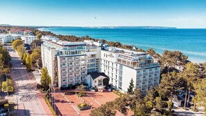 A multi-story hotel with a central courtyard, surrounded by trees and a view of the sea. - Rugard Thermal Strandhotel (Binz)