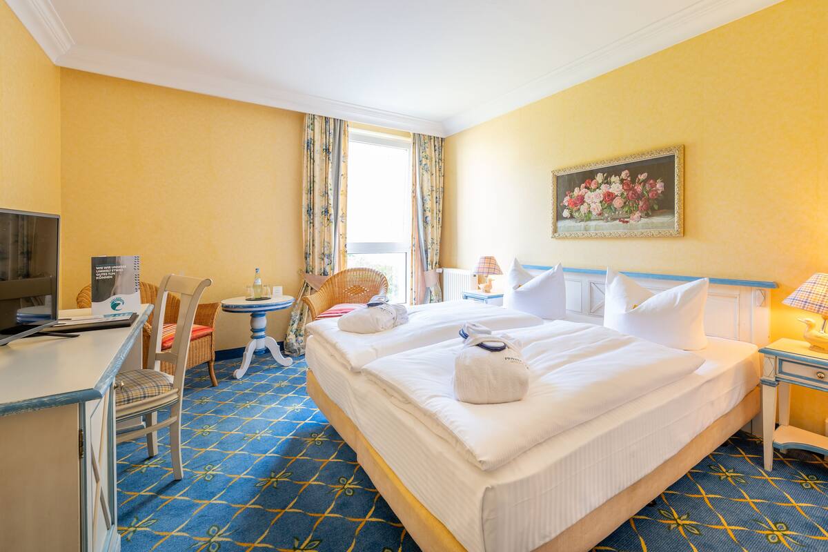Une chambre d’hôtel avec un grand lit, un bureau, une chaise, une petite table et un tableau au mur.