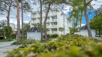 A multi-story building with balconies, surrounded by trees and greenery.