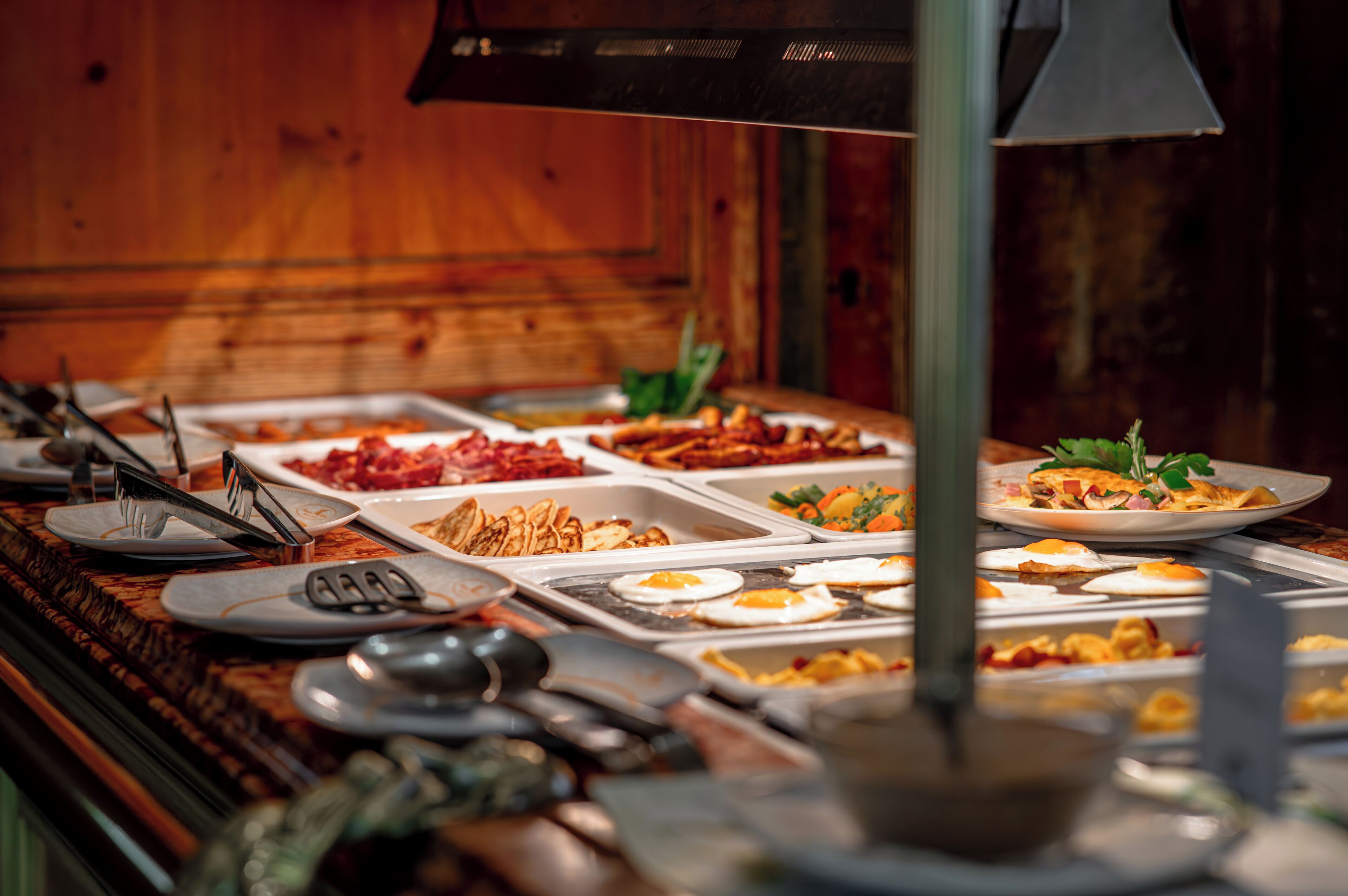 A buffet with various food options including eggs, meats, and vegetables.