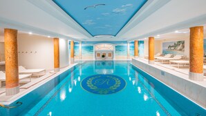 A large indoor swimming pool with a ceiling mural of seagulls and a central emblem. - Rugard Thermal Strandhotel (Binz)
