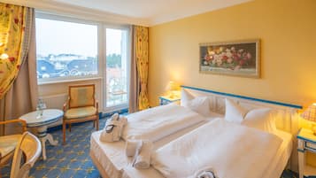 Ett hotellrum med två sängar, en stol, ett bord och en tavla på väggen.