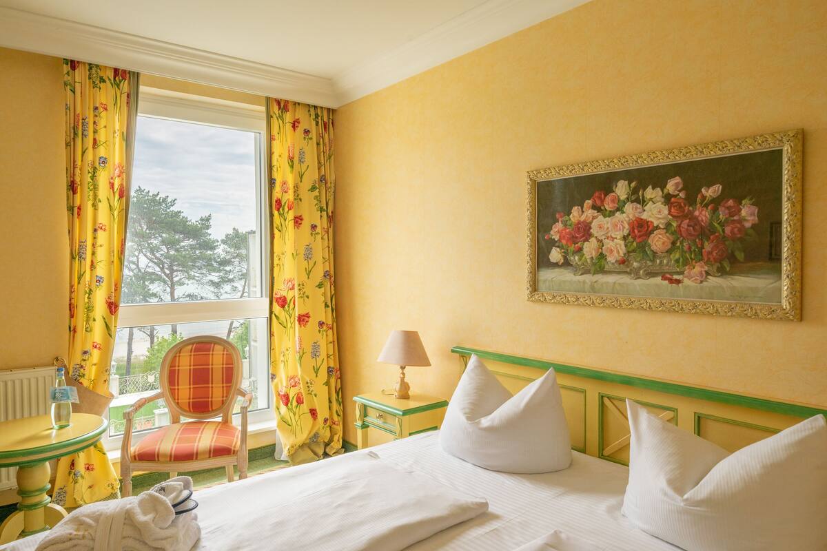 Une chambre d’hôtel avec un lit, une chaise, une table, une lampe et un tableau au mur.