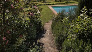 A stone pathway leading to a swimming pool surrounded by lush greenery and hills in the background. - Relais Fattoria Valle (Greve in Chianti)