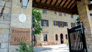 A stone building with a sign reading "Ristorante Valle" and a black gate. - Relais Fattoria Valle (Greve in Chianti)