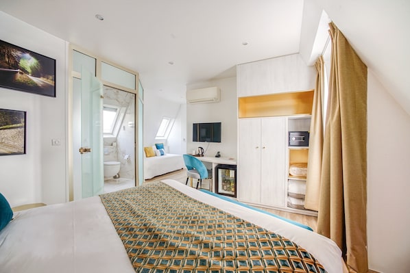 Una habitación de hotel moderna con una cama grande, un escritorio, un televisor y un armario.