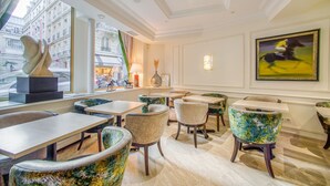 A dining area with tables and chairs, a sculpture, and artwork on the walls. - Queens Boutique Hotel (Paris)