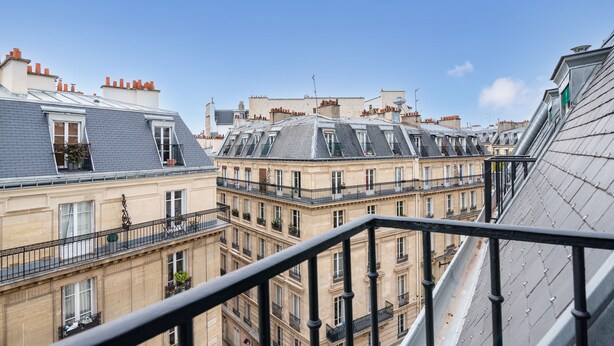 A view of a row of Parisian buildings with multiple balconies and a clear blue sky. - Queens Boutique Hotel (Paris)